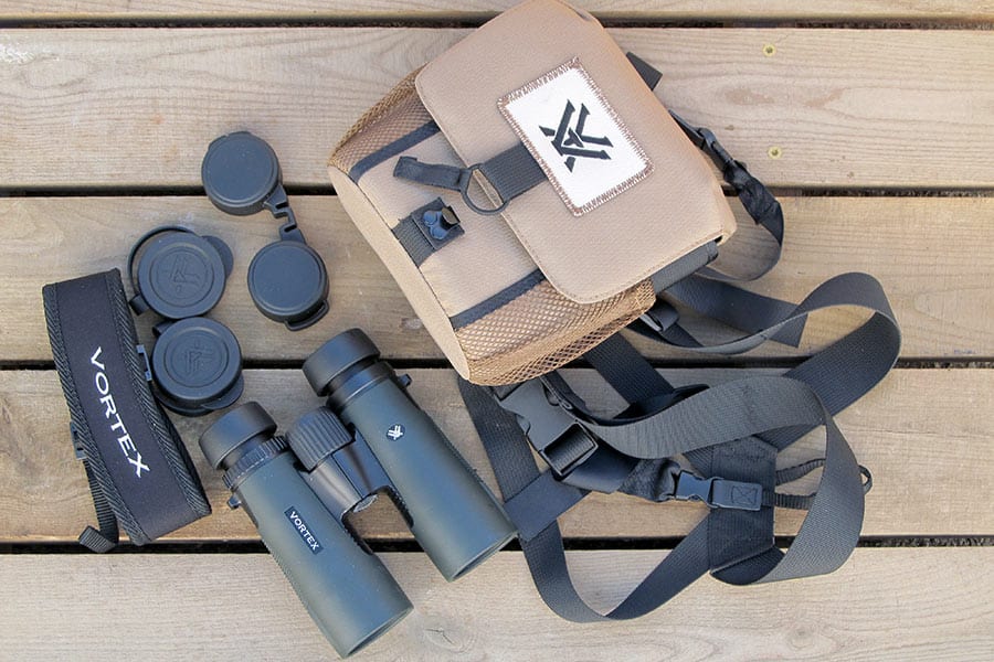 Binocular and accessories laying on wooden picnic table