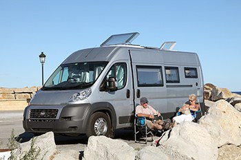 Couple sitting in chairs outside of camper van