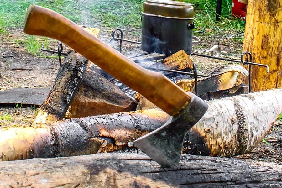 Axe stuck in a log beside a campfire
