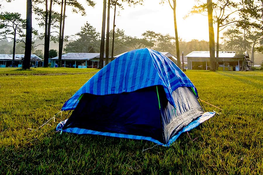 Blue tent with a striped top pitched on grass