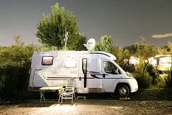 White camper van parked in front of trees