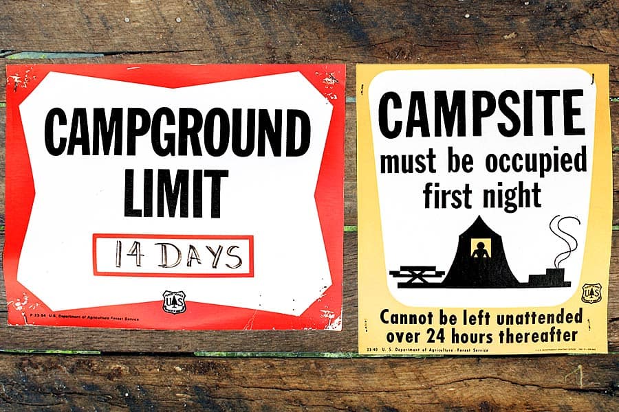 Campground rule signs stapled on wood board