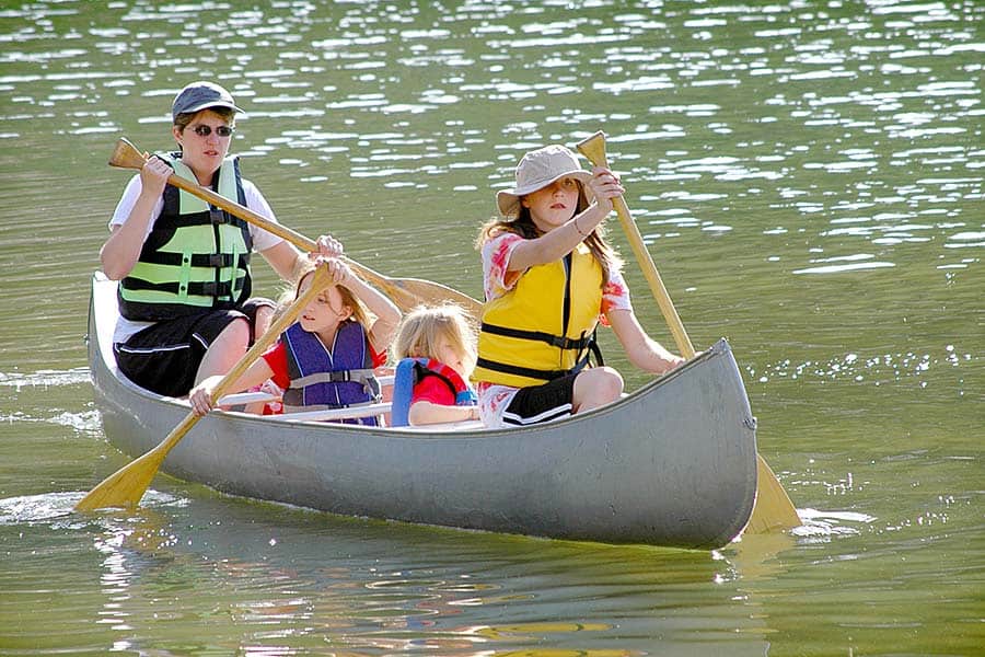 Kids paddling a canoe across lake