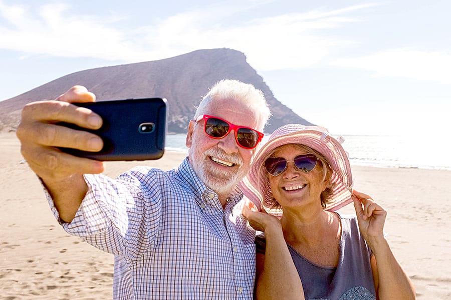 Older couple taking selfie at beach