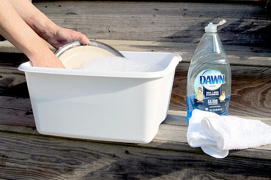 Washing dishes in white plastic tub with Dawn dish soap