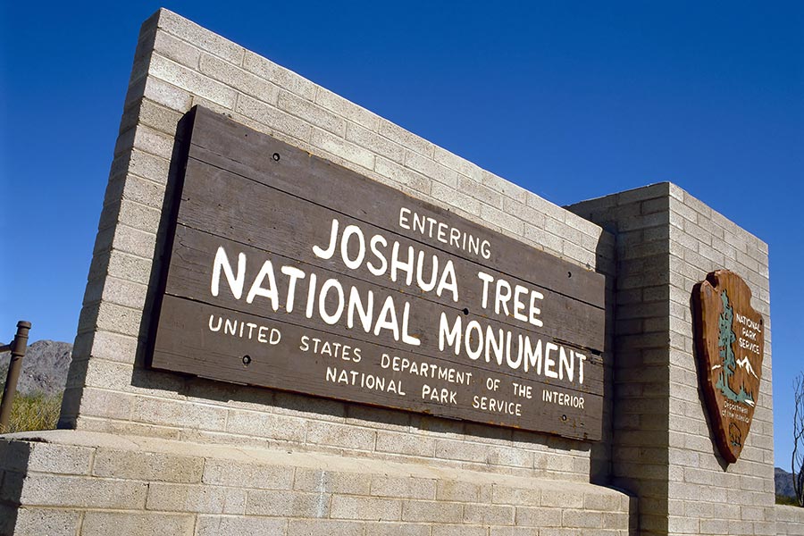 Wooden sign on block wall, entering the Joshua Tree National Monument