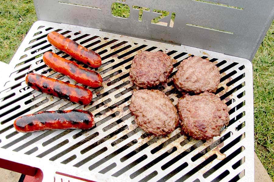 Close view of hotdogs and hamburgers on grill