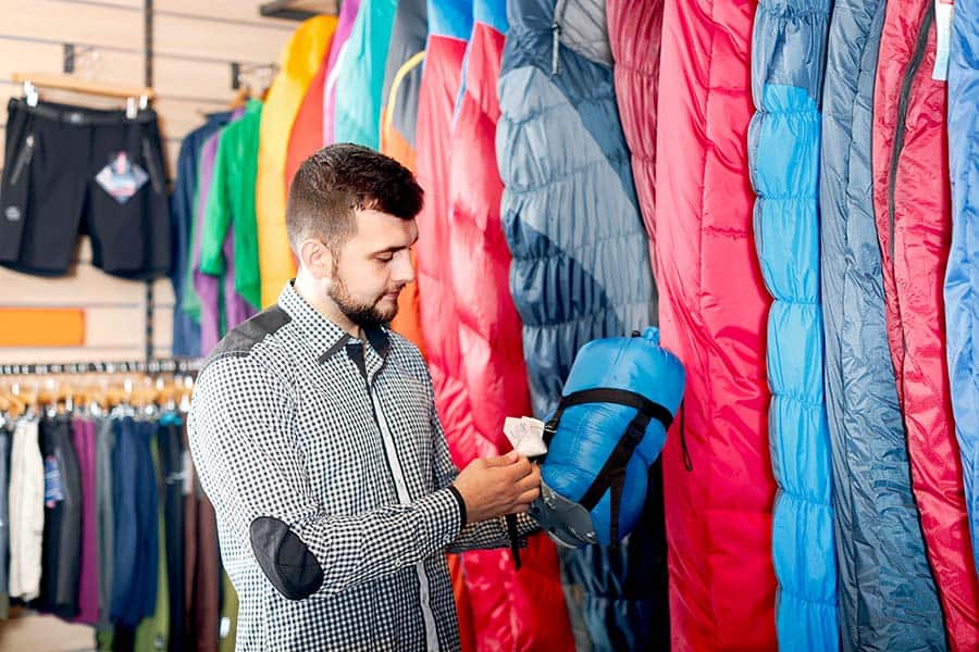 Man looking at sleeping bags in sporting goods store
