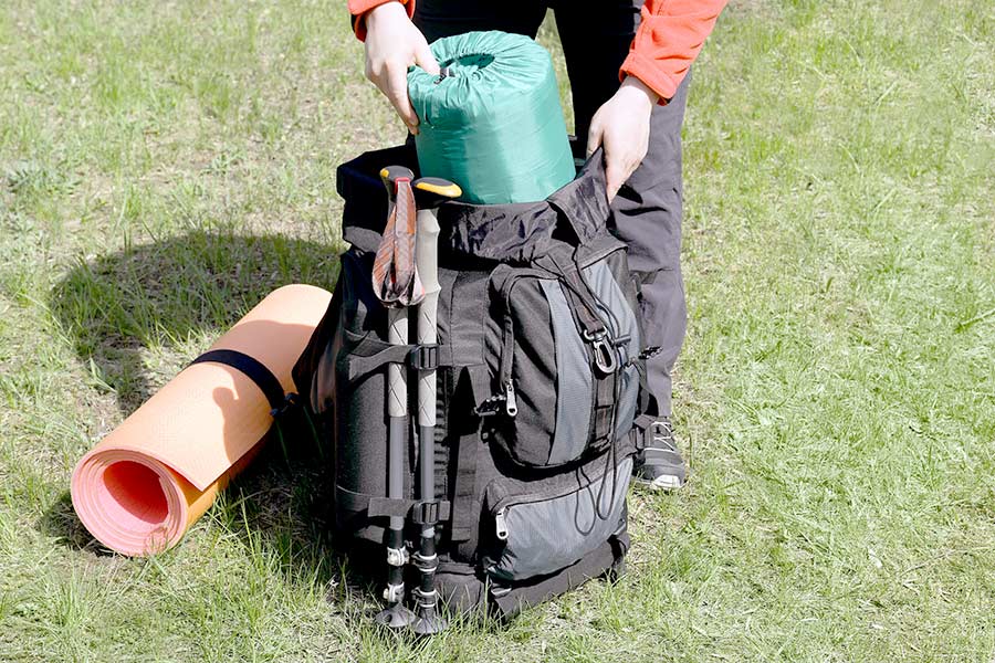 Woman putting sleeping bag in backpack